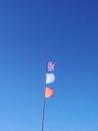 Low angle view of flag flags against clear blue sky