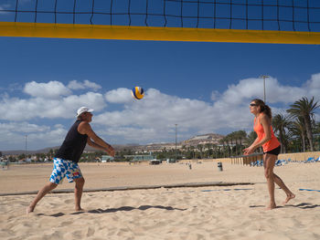 Young woman playing with ball on beach