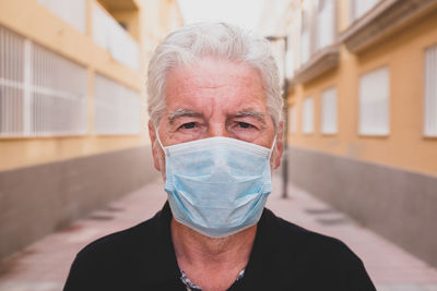 Close-up portrait of man wearing mask standing at alley