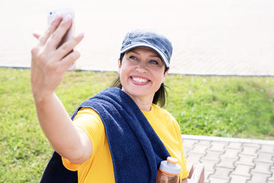 Portrait of smiling woman holding smart phone outdoors