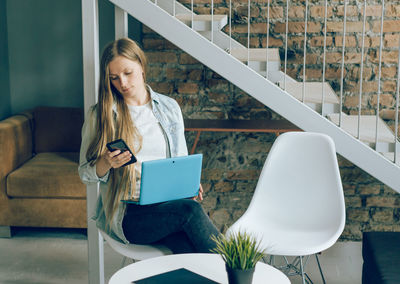 Young woman using mobile phone while sitting in office