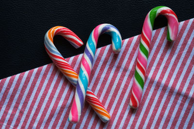 High angle view of fresh colorful candy canes on striped napkin against black background