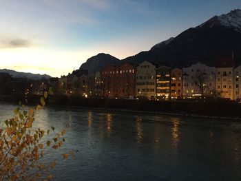 River by town against sky at dusk
