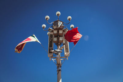 Low angle view of flags on gas light against clear blue sky at forbidden city
