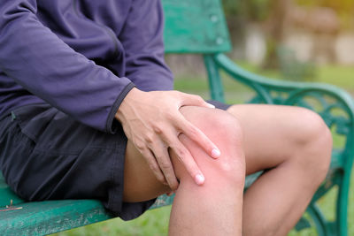 Midsection of man suffering from pain while sitting on bench