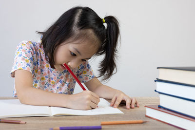 Girl drawing on book at table