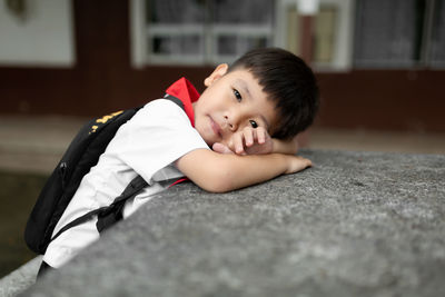 Portrait of cute boy sitting by school building