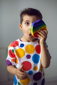 Boy in a shirt with colorful circles plays with a silicone pop it toy