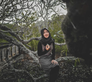 Portrait of woman standing by tree