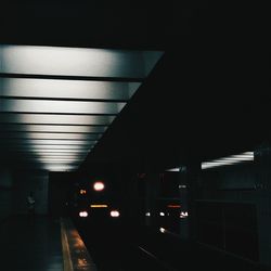 Illuminated subway station platform against sky