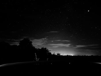 Silhouette trees on field against sky at night