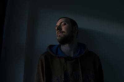 Portrait of young man looking away over black background