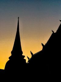 Low angle view of silhouette temple against building