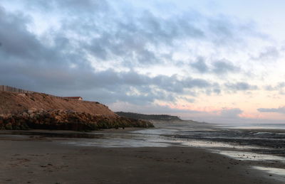 Scenic view of beach against cloudy sky