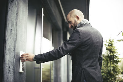 Side view of mid adult businessman entering keycode to open office door