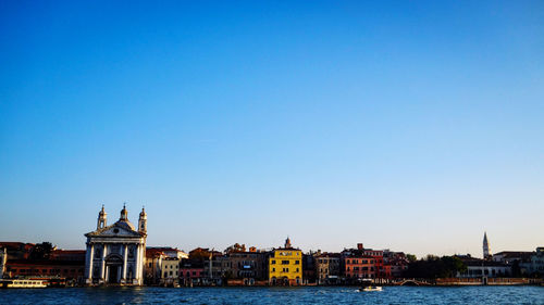 Buildings at waterfront against blue sky