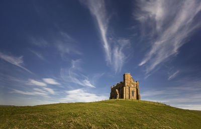 Old building on field against cloudy sky