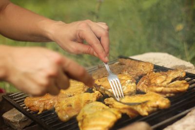 Midsection of person preparing food on barbecue grill