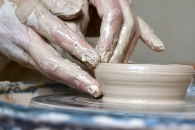 The potter makes clay earthen pot. soiled hands in the clay and the clay plate