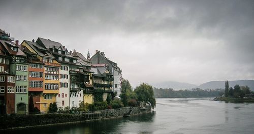 Buildings by river against sky
