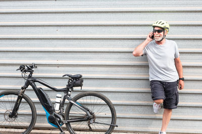 Smiling senior man with bicycle talking on phone 