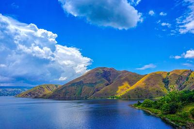 Scenic view of lake by mountains against sky