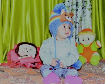 Cute baby boy with toys on bed at home