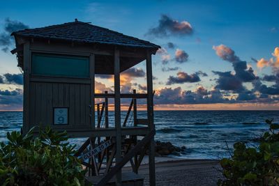 Lifeguard hut on beach against sky during sunset