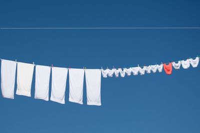 Low angle view of clothes hanging on clothesline against clear blue sky