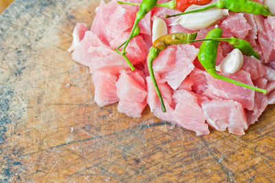 Close-up of pork with chili pepper and garlic clove on cutting board