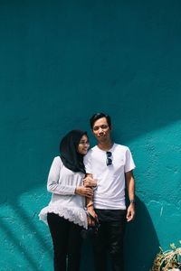 Young couple standing against blue wall