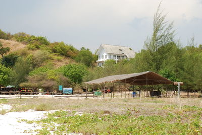 Houses on field by trees against sky