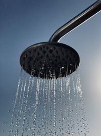 Close-up of water drops on metal against sky