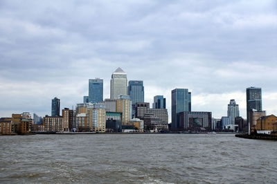 Sea by buildings against sky in city