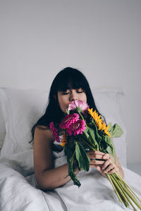 Beautiful young woman sitting on bed