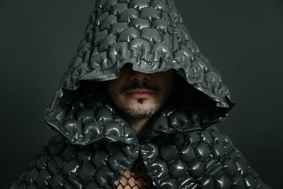 Man wearing hooded cloth against gray background