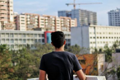 Rear view of man looking at city buildings