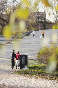 Male and female volunteers throwing plastic waste in garbage can