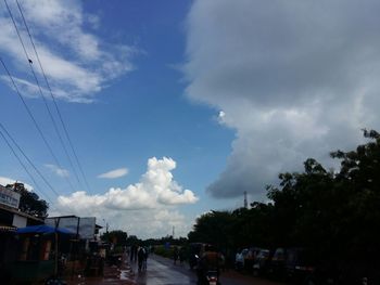 Cars on road against cloudy sky