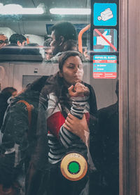 Young woman standing by glass window