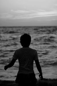Rear view of a man overlooking calm sea