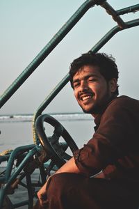 Portrait of smiling man sitting against sky