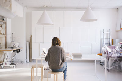 Rear view of woman sitting on chair at home