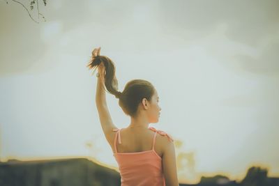 Young woman dancing against sky