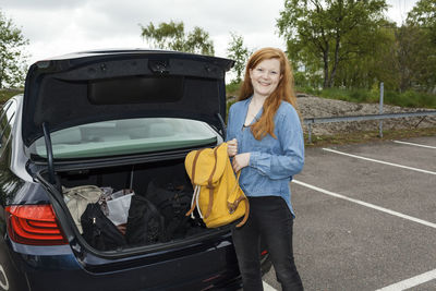 Woman putting backpack in car boot