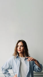 Portrait of young woman standing against white background