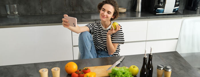 Portrait of smiling young woman using digital tablet in kitchen