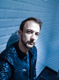 Portrait of man in jacket standing against wall