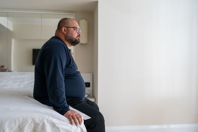 Side view of young man standing at home