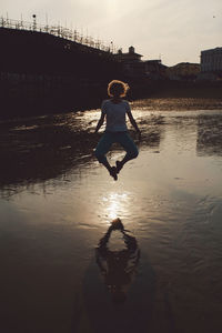 Full length of woman jumping by eastbourne pier at beach